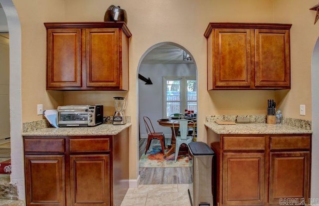 kitchen with brown cabinetry, arched walkways, and a toaster