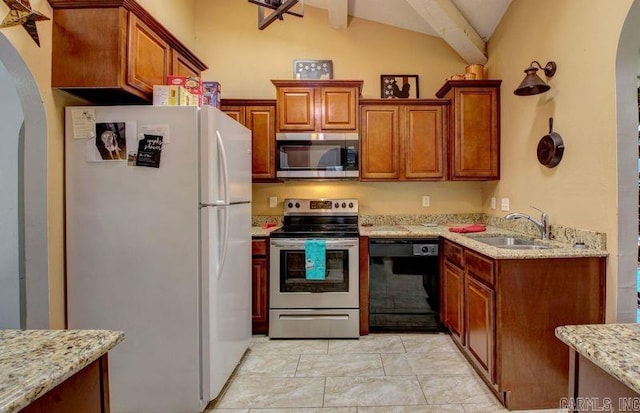 kitchen with arched walkways, light stone counters, appliances with stainless steel finishes, vaulted ceiling, and a sink