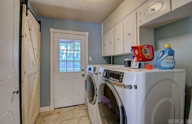 laundry room with a textured ceiling, a barn door, independent washer and dryer, and cabinet space