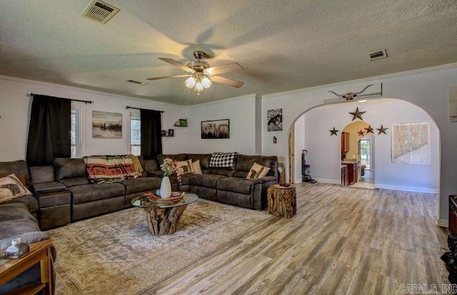 living room featuring crown molding, visible vents, arched walkways, and wood finished floors