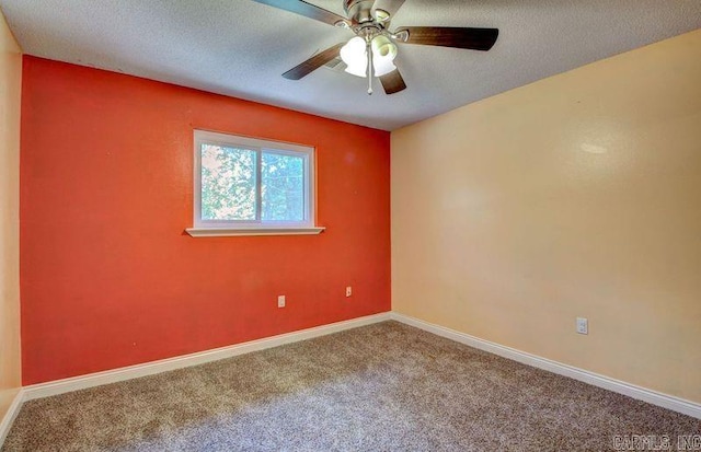 carpeted empty room with a textured ceiling, a ceiling fan, and baseboards