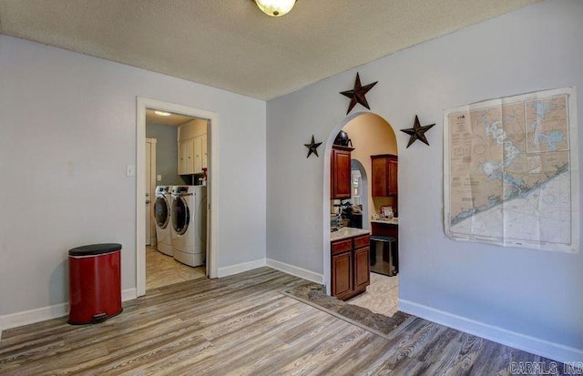 hallway with washer and dryer, a textured ceiling, and light hardwood / wood-style floors