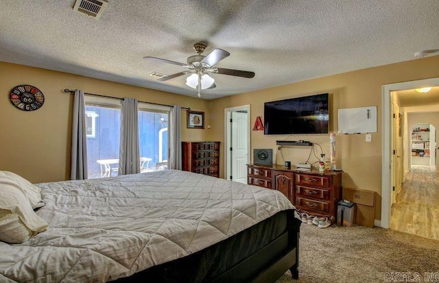 bedroom featuring ceiling fan, a textured ceiling, visible vents, and carpet flooring