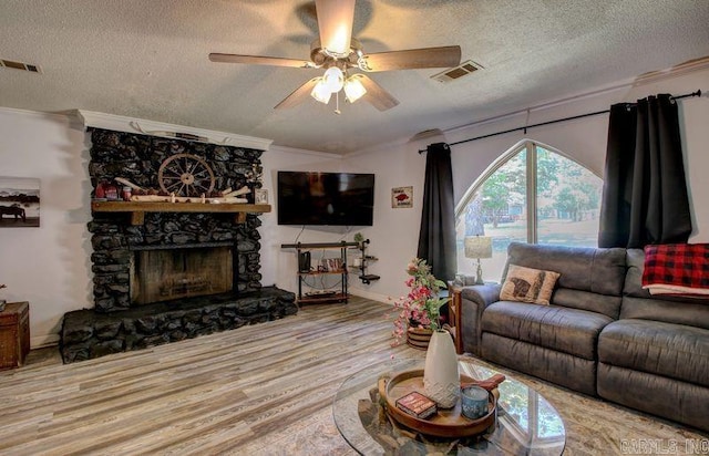 living room with ceiling fan, a fireplace, a textured ceiling, and ornamental molding