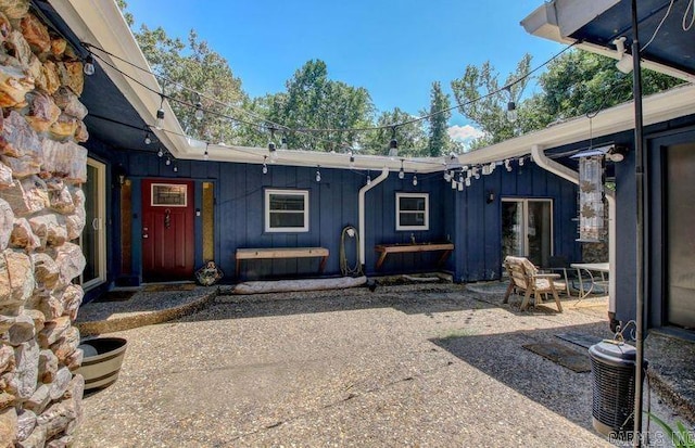 rear view of house with board and batten siding, a patio area, and central air condition unit