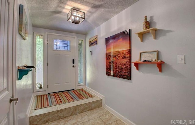 foyer entrance featuring baseboards, a textured ceiling, and tile patterned floors