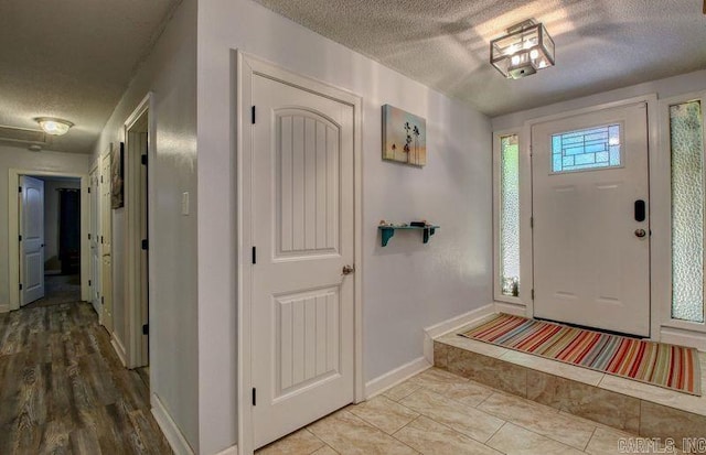 foyer featuring a textured ceiling and baseboards