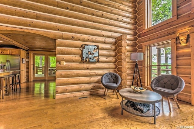 sitting room featuring log walls and wood-type flooring
