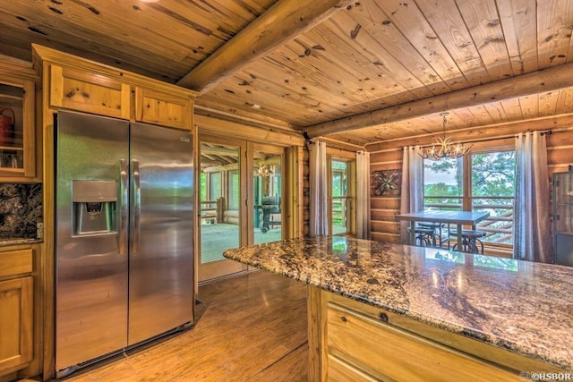 kitchen featuring pendant lighting, stainless steel refrigerator with ice dispenser, dark stone countertops, light wood-type flooring, and a chandelier