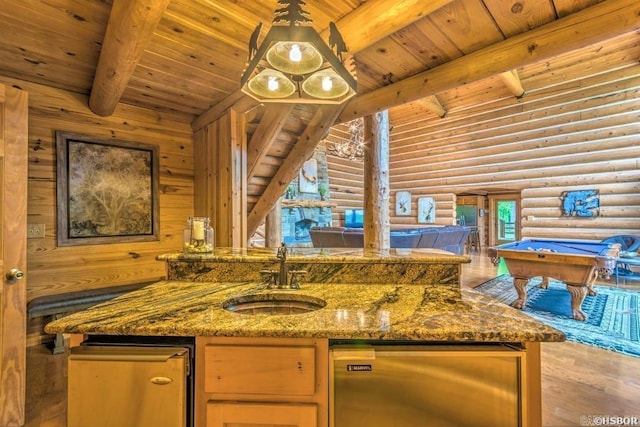 kitchen featuring dark stone countertops, billiards, sink, and log walls