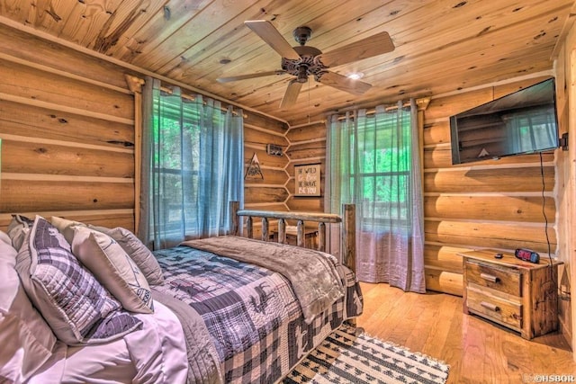 bedroom with wooden ceiling, light hardwood / wood-style flooring, ceiling fan, rustic walls, and multiple windows
