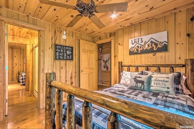 bedroom with ceiling fan, light hardwood / wood-style flooring, wood ceiling, and wood walls