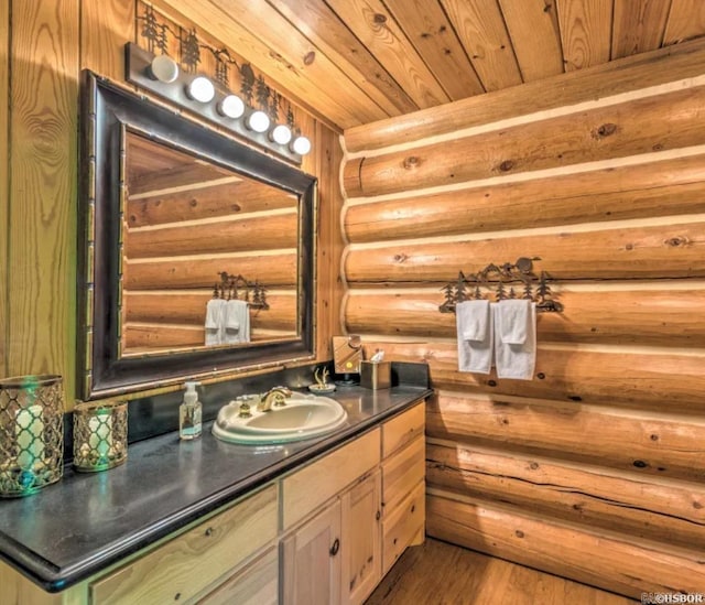 bathroom with hardwood / wood-style flooring, vanity, wooden ceiling, and log walls