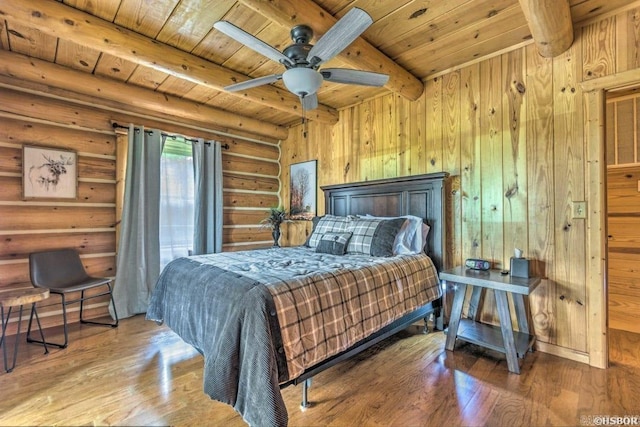 bedroom featuring wooden ceiling, hardwood / wood-style flooring, ceiling fan, rustic walls, and beam ceiling