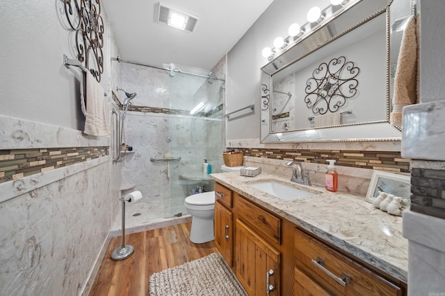 bathroom featuring decorative backsplash, vanity, wood-type flooring, toilet, and a shower with shower door