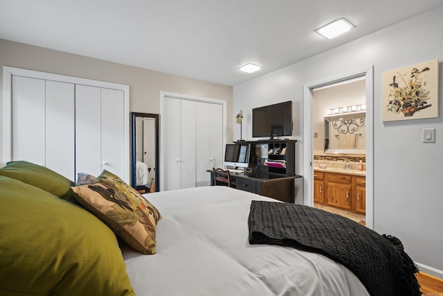 bedroom featuring hardwood / wood-style flooring, two closets, sink, and ensuite bath