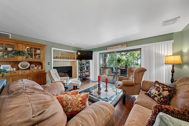 living room featuring a tiled fireplace and hardwood / wood-style flooring