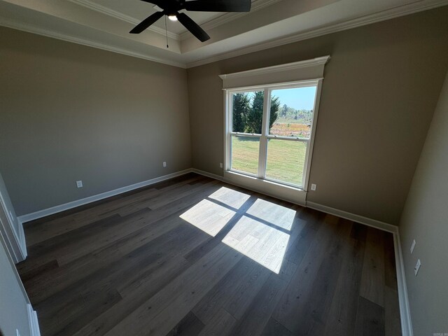 empty room featuring dark hardwood / wood-style flooring, a tray ceiling, ceiling fan, and crown molding