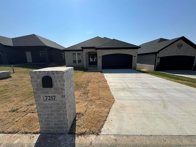 view of front of property with a front yard, a garage, and central air condition unit