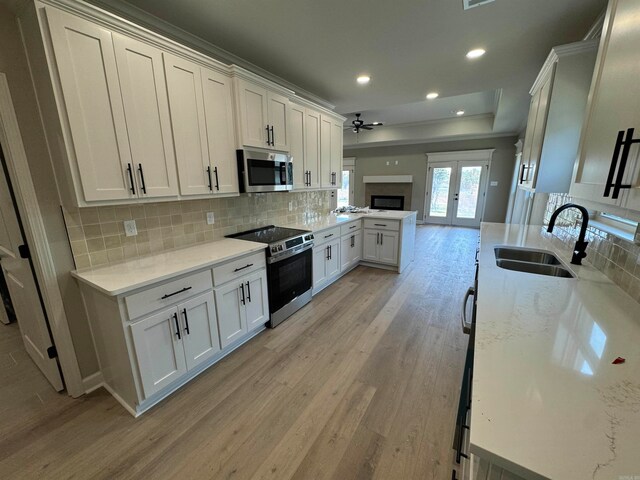 kitchen with white cabinetry, sink, french doors, appliances with stainless steel finishes, and light wood-type flooring