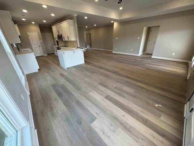 kitchen with light wood-type flooring, backsplash, white cabinetry, and sink