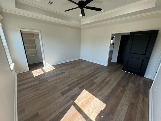 spare room featuring a raised ceiling, crown molding, and dark hardwood / wood-style flooring