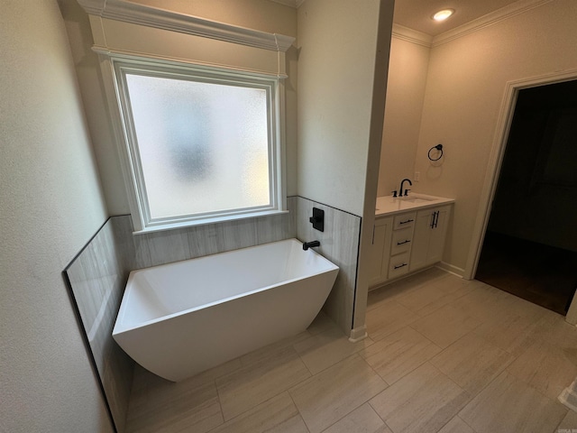 bathroom with ornamental molding, a washtub, and vanity