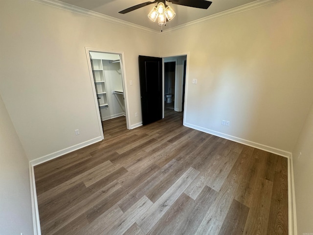 unfurnished bedroom with ceiling fan, hardwood / wood-style flooring, ornamental molding, and a spacious closet