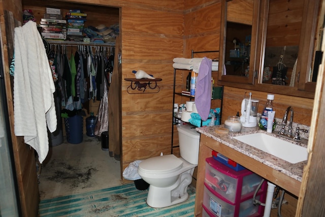 bathroom with toilet, wooden walls, and sink