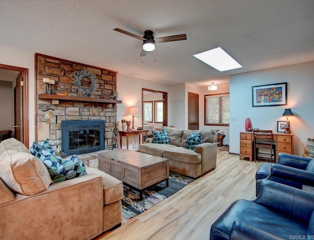 living room featuring a fireplace, a textured ceiling, hardwood / wood-style flooring, and ceiling fan