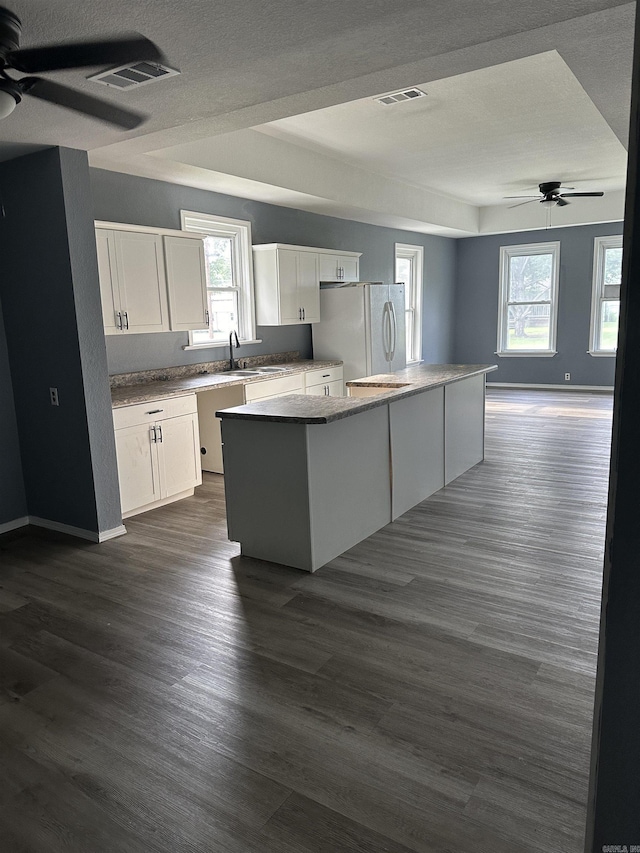 kitchen with white cabinets, white refrigerator, a center island, and a wealth of natural light