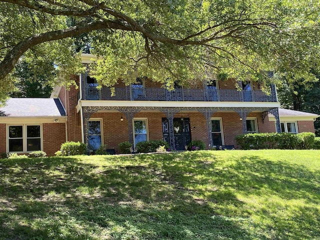 view of front facade with a balcony and a front lawn