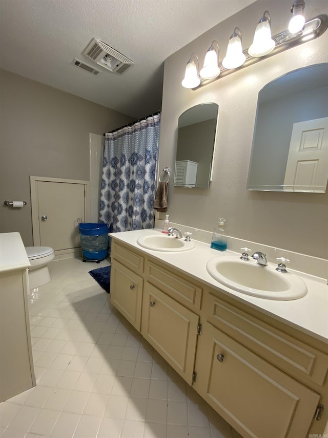 bathroom featuring tile patterned flooring, vanity, a textured ceiling, and toilet