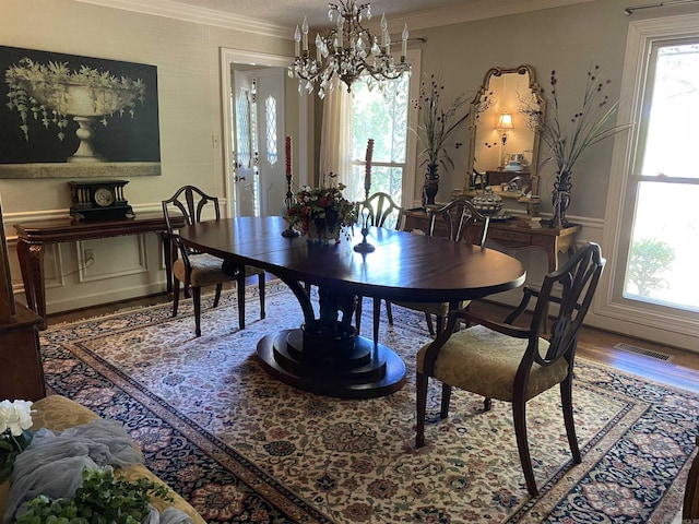 dining area featuring a notable chandelier, wood-type flooring, and ornamental molding