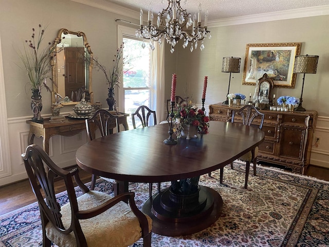 dining space with hardwood / wood-style flooring, ornamental molding, a textured ceiling, and a chandelier