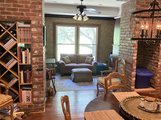 living room with ceiling fan with notable chandelier, hardwood / wood-style flooring, and ornamental molding