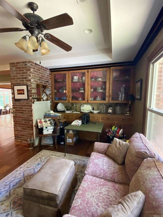 living room featuring dark hardwood / wood-style floors, ceiling fan, and a raised ceiling