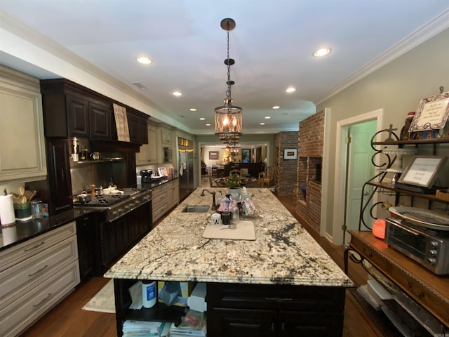 kitchen with a large island, sink, light stone countertops, a chandelier, and ornamental molding