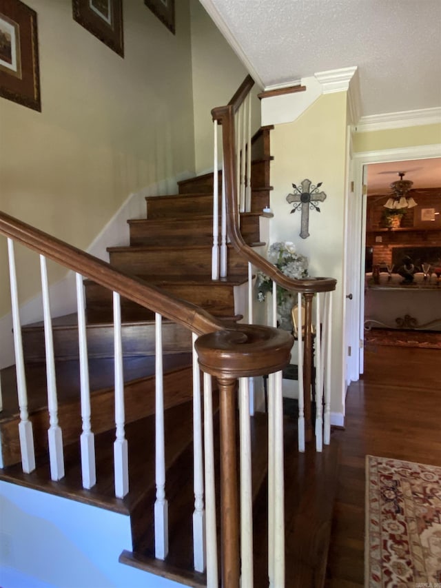 staircase with crown molding, a textured ceiling, and hardwood / wood-style flooring