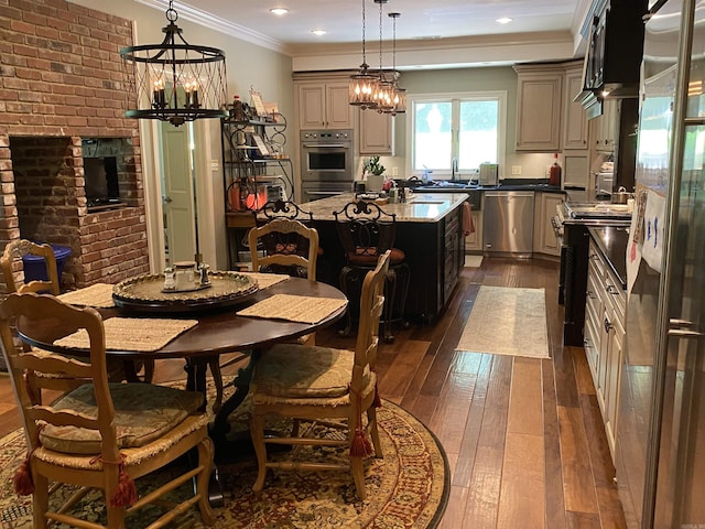 dining area featuring ornamental molding, sink, an inviting chandelier, a fireplace, and dark hardwood / wood-style floors