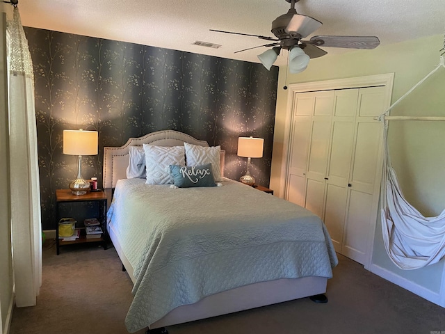 bedroom with ceiling fan, dark carpet, a textured ceiling, and a closet