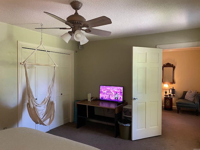 bedroom with a textured ceiling, a closet, dark carpet, and ceiling fan