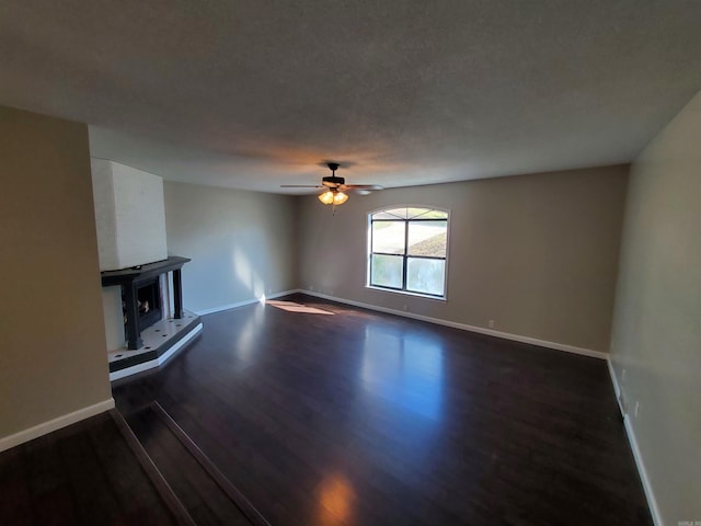 unfurnished living room featuring a textured ceiling, dark hardwood / wood-style floors, and ceiling fan