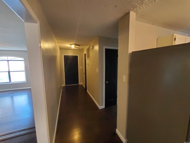 hall featuring dark wood-type flooring and a textured ceiling