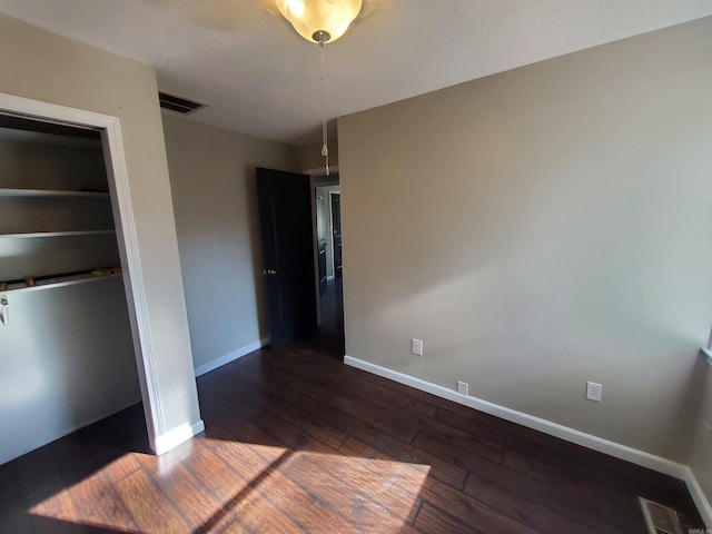 unfurnished bedroom featuring dark hardwood / wood-style flooring and a closet