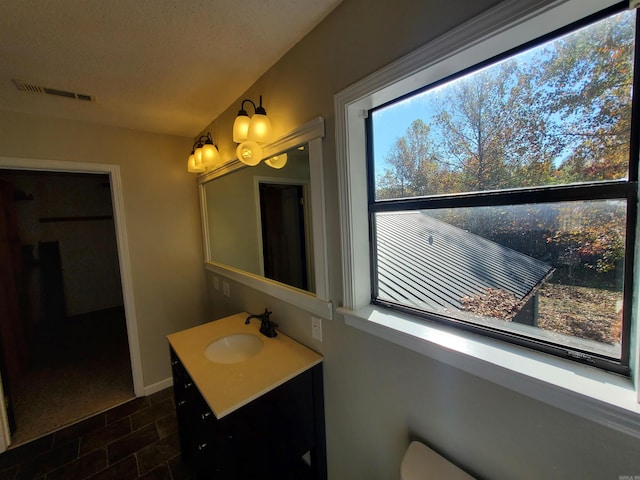 bathroom with tile patterned flooring, plenty of natural light, a textured ceiling, and vanity