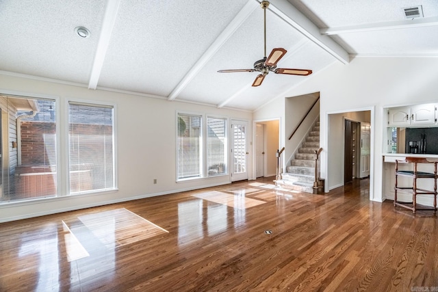 unfurnished living room featuring ceiling fan, lofted ceiling with beams, a textured ceiling, and hardwood / wood-style flooring