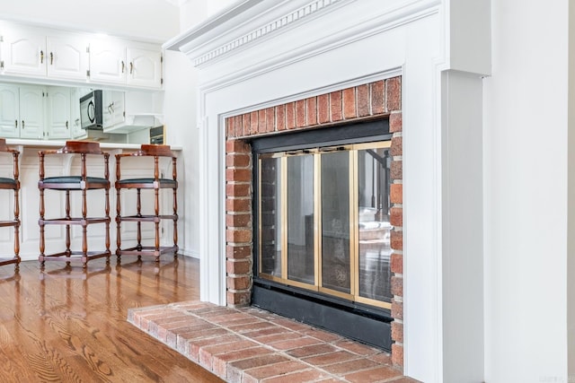 details with hardwood / wood-style floors and a brick fireplace