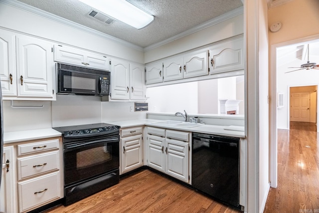 kitchen with white cabinetry, sink, and black appliances