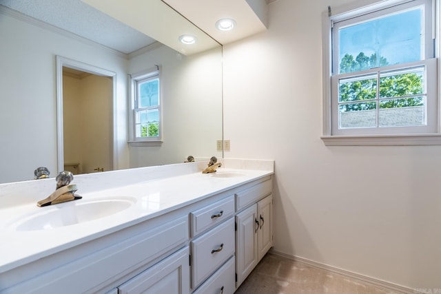 bathroom with toilet, vanity, crown molding, and a healthy amount of sunlight